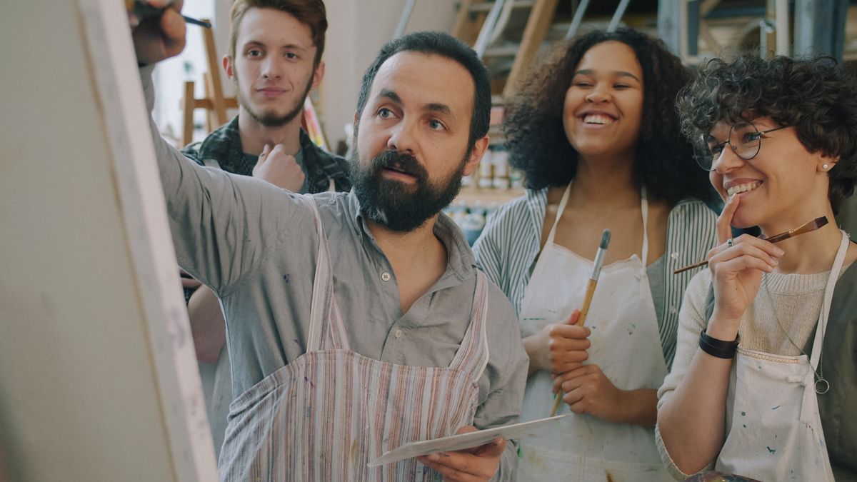 A small studio group reviewing a painting in progress together